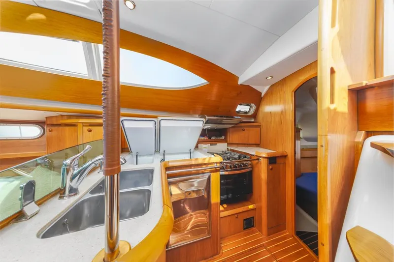 Maka Le'a Yacht Photos Pics 2006 Jeanneau DS yacht interior with modern kitchen, wooden cabinetry, and stainless steel sink.