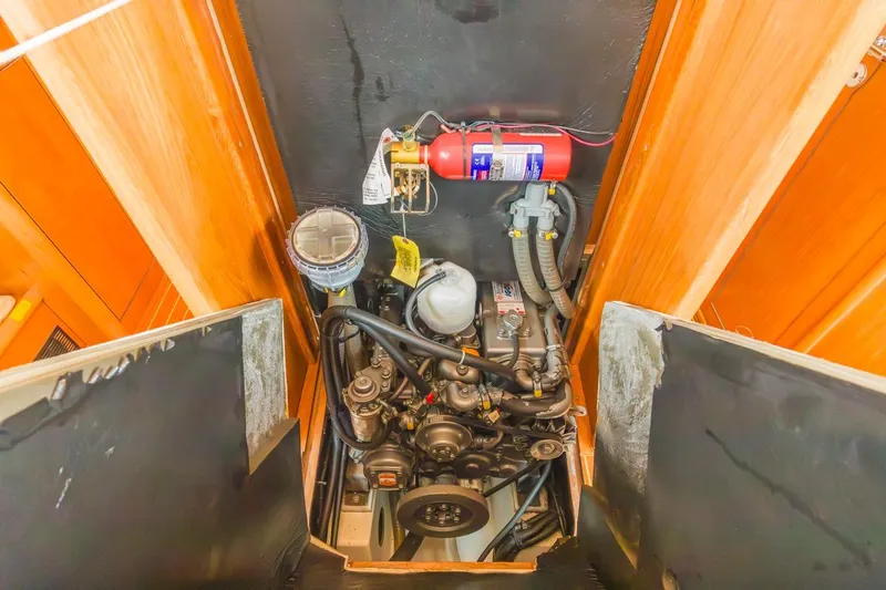 Maka Le'a Yacht Photos Pics Engine compartment of a 2006 Jeanneau DS sailboat, featuring mechanical components and fire extinguisher.