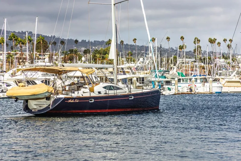 Maka Le'a Yacht Photos Pics Sailboat Jeanneau DS 2006 in marina, surrounded by palm trees and other boats.