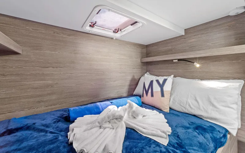 Mona Lisa Yacht Photos Pics 2024 Fountaine Pajot MY.6 cabin with cozy bedding and modern wood paneling.