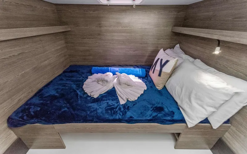 Mona Lisa Yacht Photos Pics 2024 Fountaine Pajot MY.6 cabin with cozy bed, blue blanket, and decorative pillows.