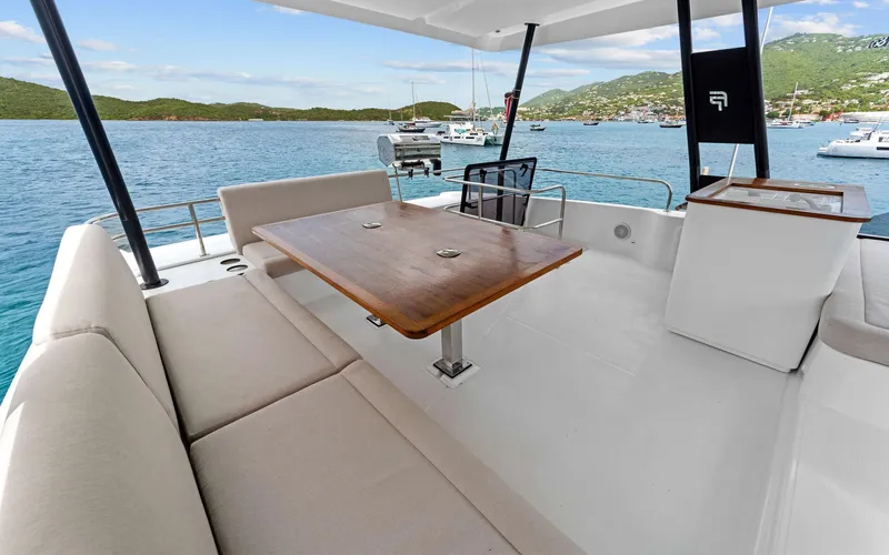 Mona Lisa Yacht Photos Pics 2024 Fountaine Pajot MY.6 yacht deck with seating and table, overlooking serene waters.