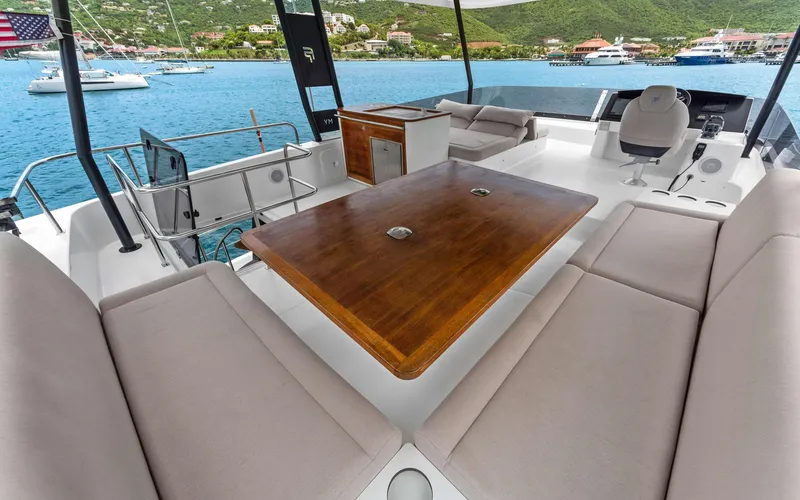 Mona Lisa Yacht Photos Pics Luxurious 2024 Fountaine Pajot MY.6 yacht deck with seating and table, overlooking serene waters.