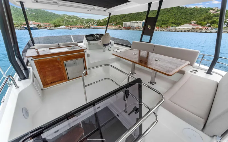 Mona Lisa Yacht Photos Pics 2024 Fountaine Pajot MY.6 yacht deck with seating, table, and scenic waterfront view.