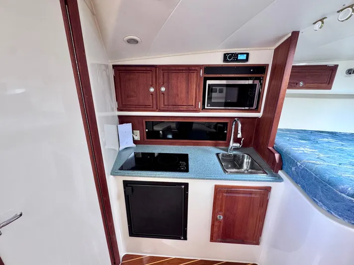 Triple Play Yacht Photos Pics 2005 Carolina Classic 35 boat interior kitchen with wood cabinets, sink, and microwave.