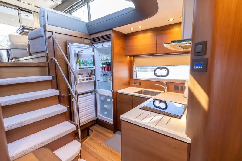 Quick Decision Yacht Photos Pics Modern kitchen interior of 2020 Princess V50 yacht with open fridge and wooden cabinetry.