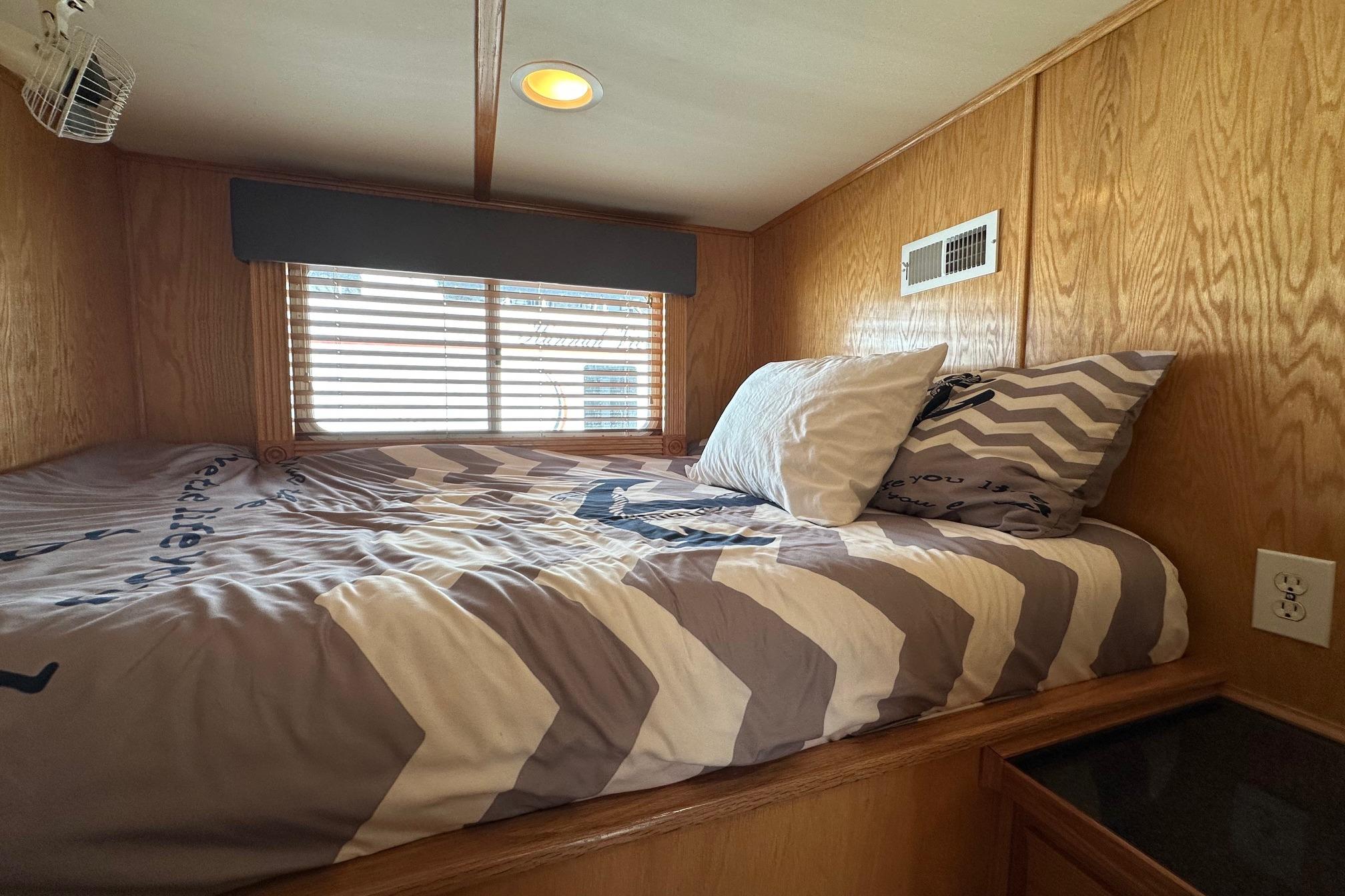 Cozy bedroom in 2004 Lakeview 16x68 houseboat with chevron bedding and wood paneling.