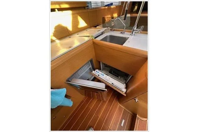  Yacht Photos Pics Interior of 2010 Jeanneau 57 yacht kitchen with open dishwasher and wooden flooring.