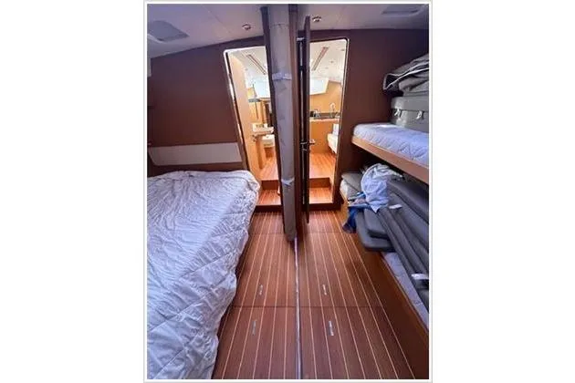  Yacht Photos Pics Interior of 2010 Jeanneau 57 yacht, featuring cozy cabin with wooden flooring and bedding.