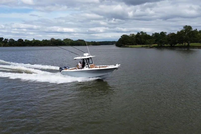  Yacht Photos Pics 2021 Sea Hunt Gamefish 27 Coffin Box cruising on a scenic lake under cloudy skies.