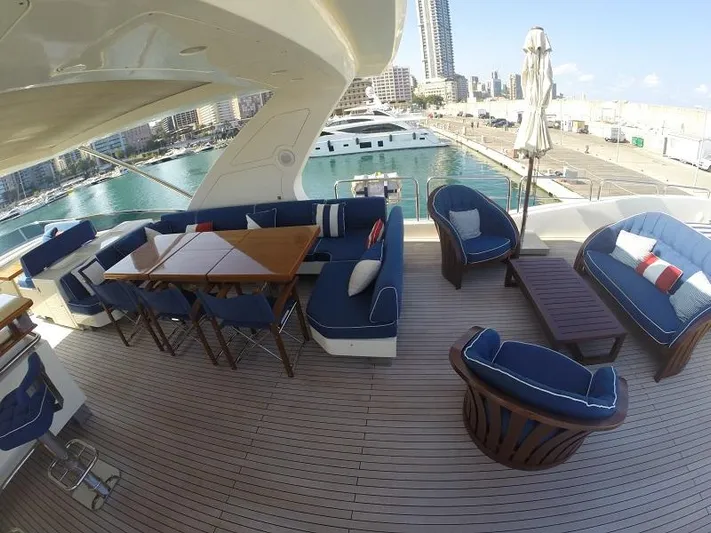  Yacht Photos Pics Luxury yacht deck with blue seating, wooden table, and marina view; Azimut 95, 2008 model.
