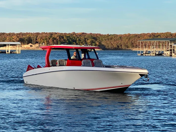  Yacht Photos Pics 2024 Fountain 38 SCX boat cruising on a lake with a scenic background.