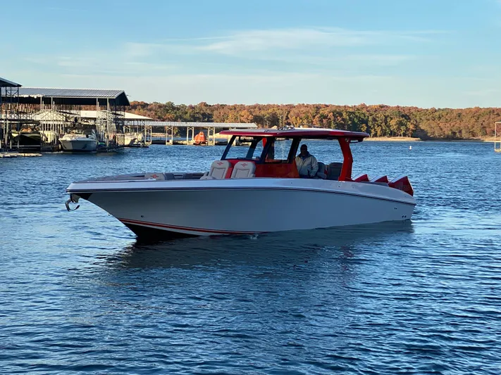  Yacht Photos Pics 2024 Fountain 38 SCX boat cruising on a lake with docks in the background.