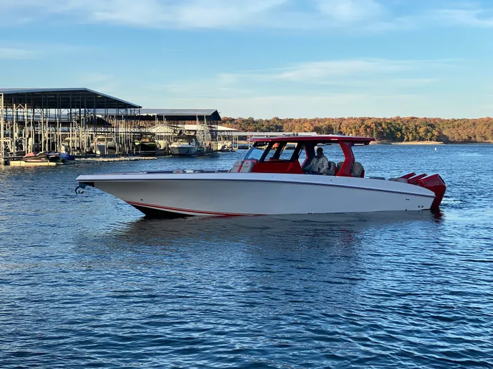  Yacht Photos Pics 2024 Fountain 38 SCX boat cruising on a serene lake near a marina.