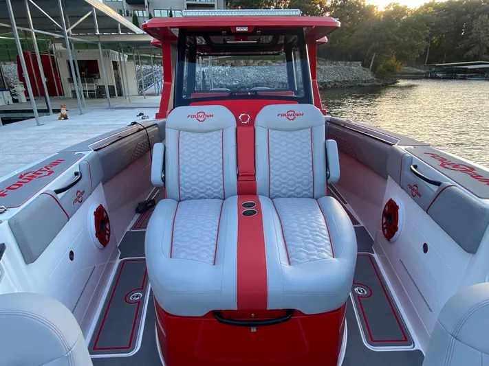  Yacht Photos Pics 2024 Fountain 38 SCX boat interior with red and gray seating, docked by the water.