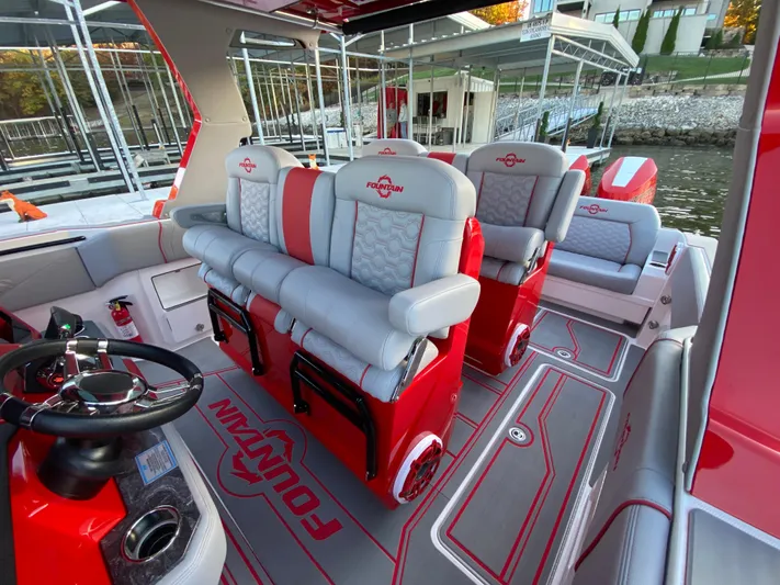  Yacht Photos Pics 2024 Fountain 38 SCX boat interior with red and gray seating, steering wheel, and logo detailing.