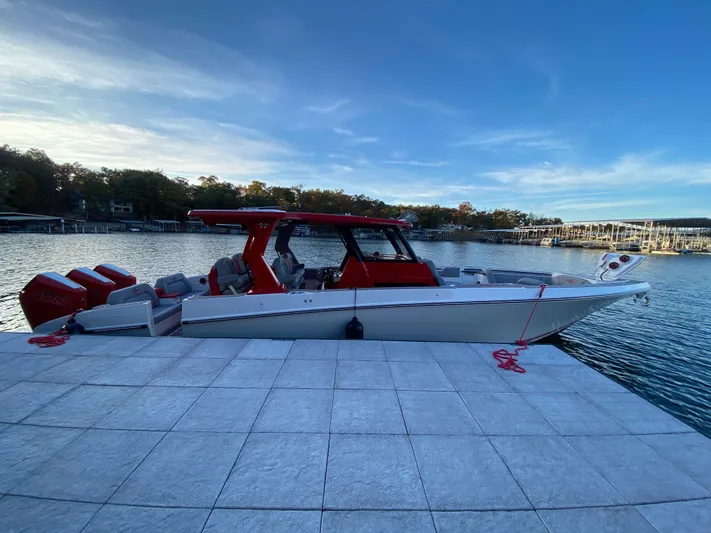  Yacht Photos Pics 2024 Fountain 38 SCX boat docked by a serene lake under a clear blue sky.