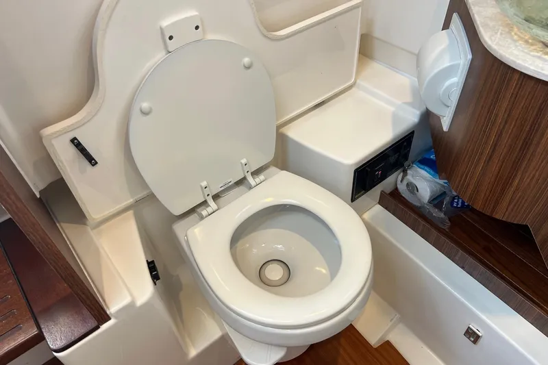  Yacht Photos Pics 2024 Pursuit S 328 Sport boat bathroom with toilet and wooden accents.