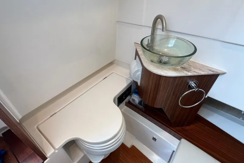  Yacht Photos Pics 2024 Pursuit S 328 Sport boat bathroom with modern glass sink and compact toilet.