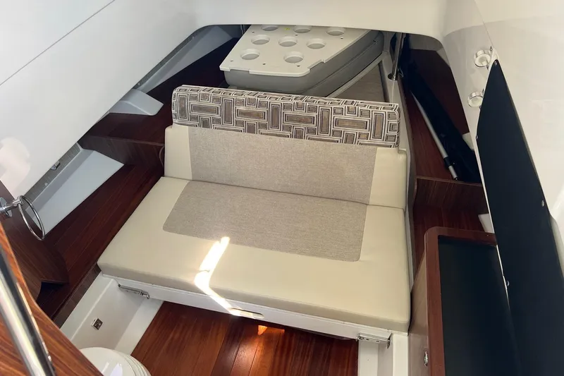 Yacht Photos Pics 2024 Pursuit S 328 Sport cabin interior with cushioned seating and wooden flooring.