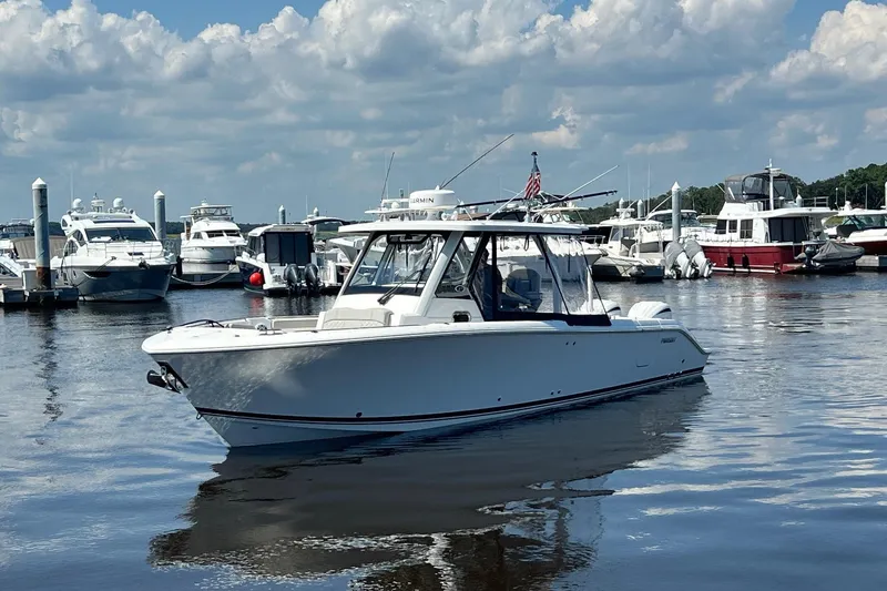  Yacht Photos Pics 2024 Pursuit S 328 Sport boat docked in a marina under a cloudy sky.