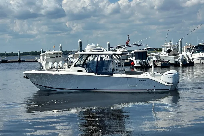  Yacht Photos Pics 2024 Pursuit S 328 Sport boat docked in a marina under a cloudy sky.