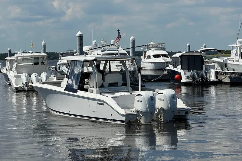  Yacht Photos Pics 2024 Pursuit S 328 Sport boat docked in a marina with other vessels.