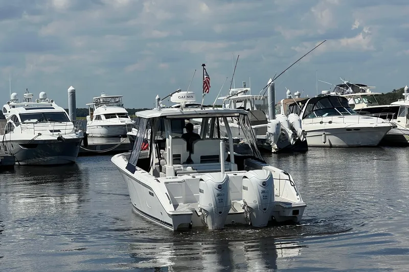  Yacht Photos Pics 2024 Pursuit S 328 Sport boat docked among other yachts in a marina.