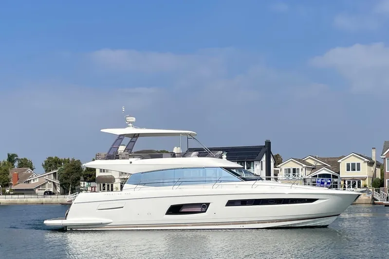 " La Bella Vita" Yacht Photos Pics 2017 Prestige 560 Flybridge yacht cruising near waterfront homes under a clear blue sky.