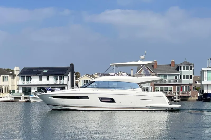 " La Bella Vita" Yacht Photos Pics 2017 Prestige 560 Flybridge yacht cruising near waterfront homes under a clear blue sky.