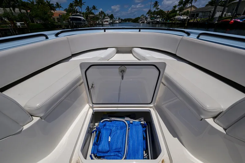  Yacht Photos Pics 2022 Fountain 34 CC boat with open storage compartment, blue bag inside, docked on a sunny day.