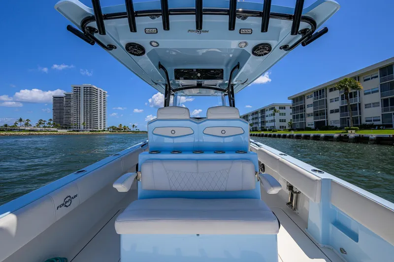  Yacht Photos Pics 2022 Fountain 34 CC boat interior with blue seating, on a sunny waterfront.