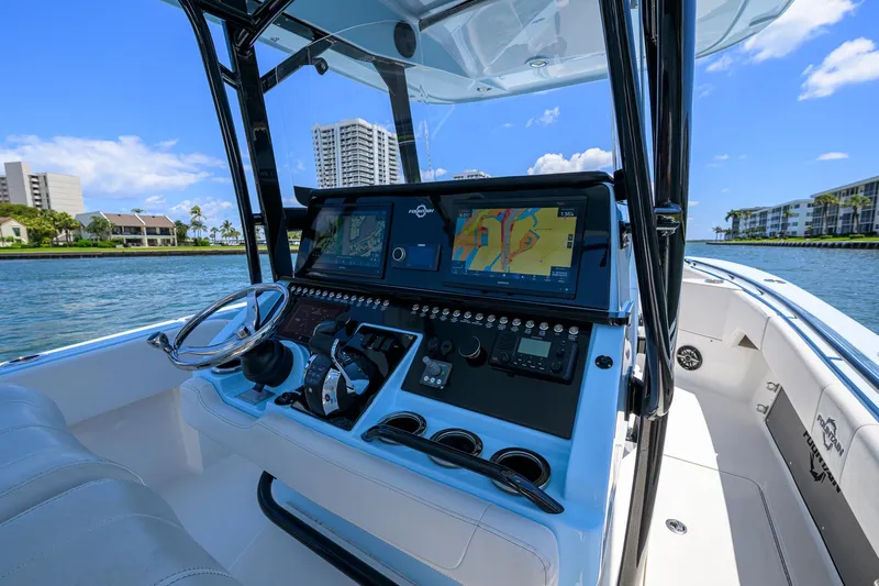  Yacht Photos Pics 2022 Fountain 34 CC boat cockpit with advanced navigation system, steering wheel, and waterfront view.