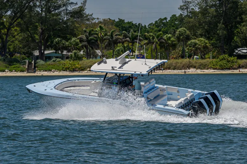  Yacht Photos Pics 2022 Fountain 34 CC boat cruising on water near a lush, tree-lined shore.