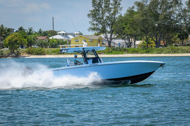  Yacht Photos Pics 2022 Fountain 34 CC boat speeding on water near a tropical shoreline.