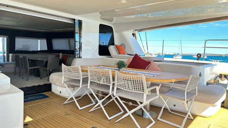  Yacht Photos Pics Luxurious Lagoon 65 yacht deck with dining area, modern seating, and ocean view, 2022 model.
