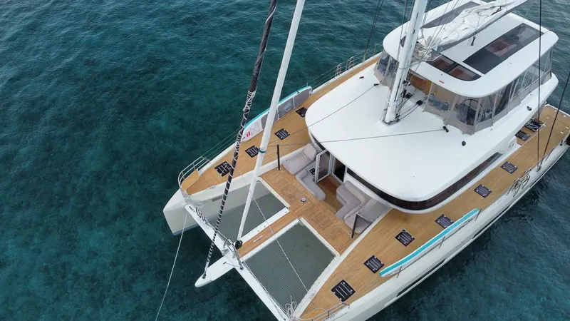  Yacht Photos Pics 2022 Lagoon 65 catamaran on clear blue water, showcasing spacious deck and modern design.