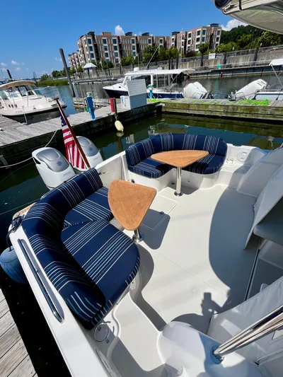 Mr. Sandman Yacht Photos Pics 2023 Back Cove 34O boat with striped seating and wooden tables at a marina.
