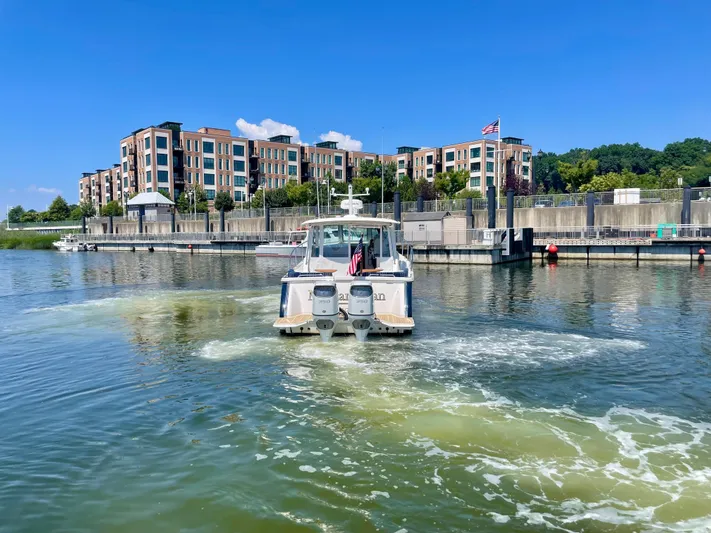 Mr. Sandman Yacht Photos Pics 2023 Back Cove 34O boat cruising in a marina with modern buildings in the background.