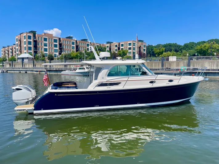 Mr. Sandman Yacht Photos Pics 2023 Back Cove 34O boat docked in marina, modern buildings in background.