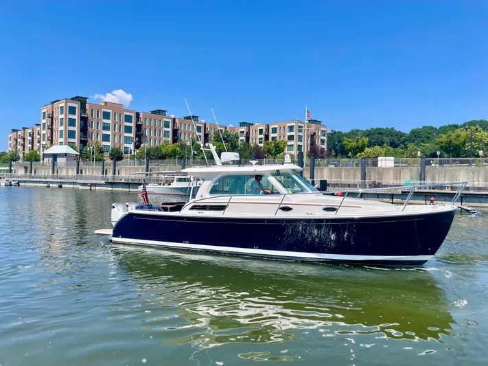 Mr. Sandman Yacht Photos Pics 2023 Back Cove 34O boat docked in a marina with modern buildings in the background.