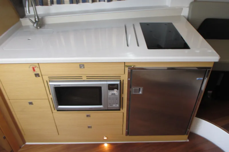 Worth Pursuit Yacht Photos Pics Compact kitchen area in 2013 Pursuit SC 365i Sport Coupe with microwave and stainless steel fridge.