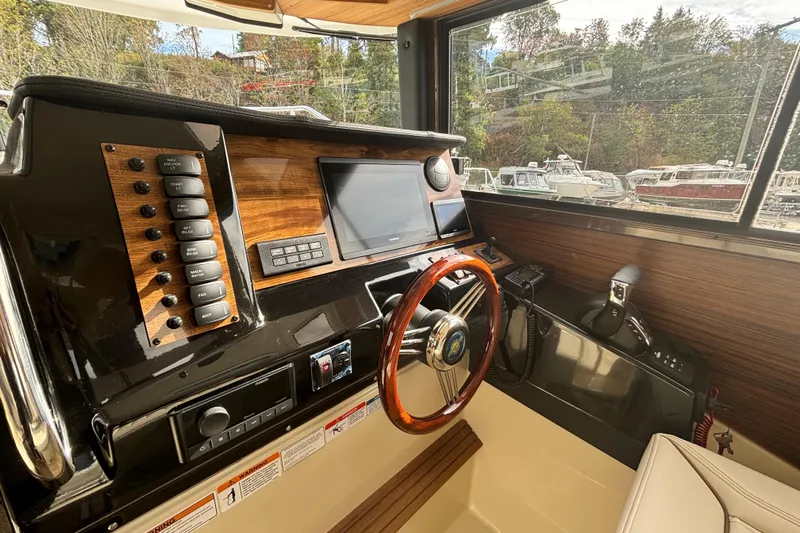  Yacht Photos Pics 2026 Ranger Tugs R-27 helm with wood accents, modern controls, and steering wheel.