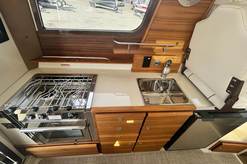  Yacht Photos Pics 2026 Ranger Tugs R-27 galley with stove, sink, and wooden cabinetry.