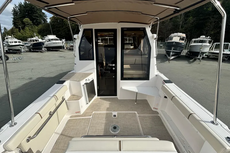  Yacht Photos Pics 2026 Ranger Tugs R-27 boat interior with seating and canopy, docked outdoors.