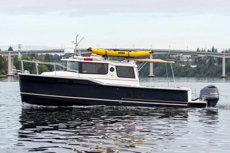  Yacht Photos Pics Manufacturer Provided Image: 2025 Ranger Tugs R-27 boat cruising on a calm river with a bridge in the background.