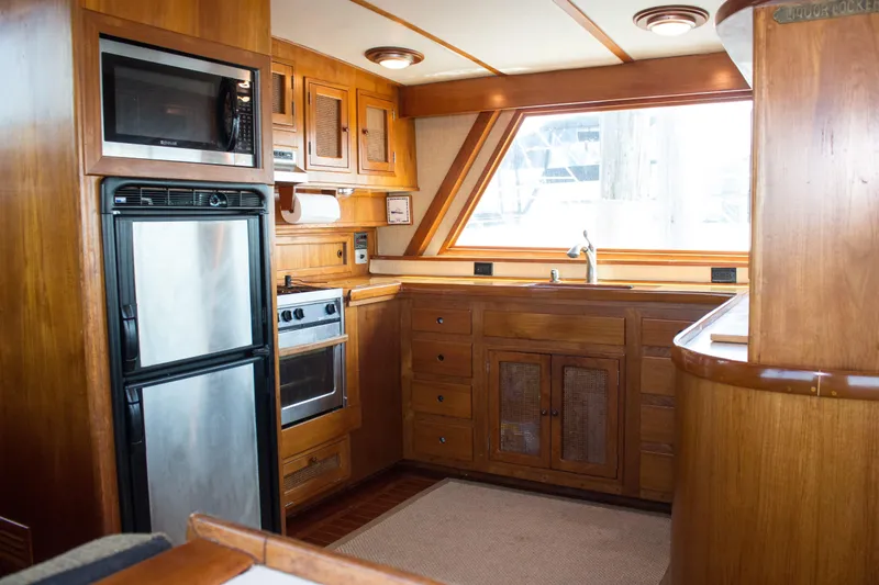Gitana Yacht Photos Pics 1986 Wilbur Hunt Yachts kitchen interior with wood cabinetry, stainless appliances, and large window.