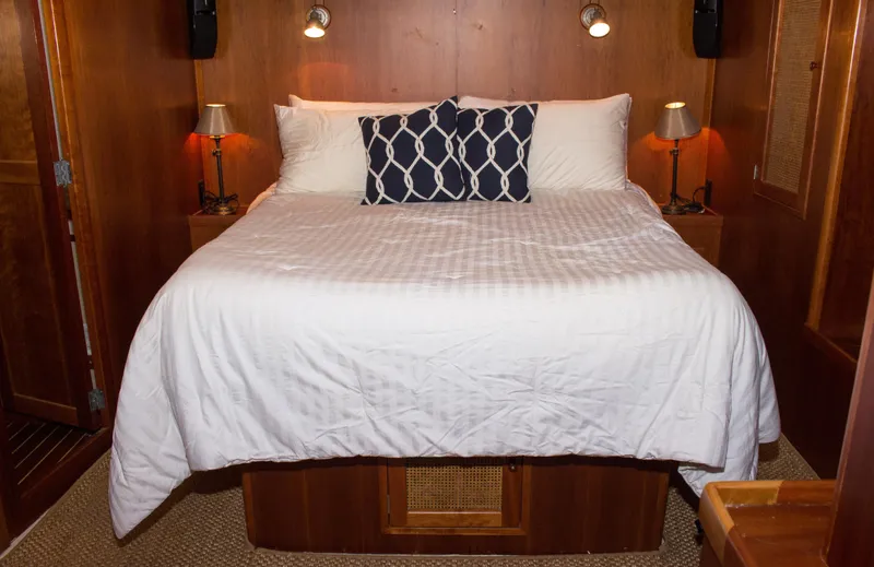 Gitana Yacht Photos Pics Luxurious cabin bedroom in 1986 Wilbur Hunt Yachts, featuring cozy bedding and elegant wood paneling.
