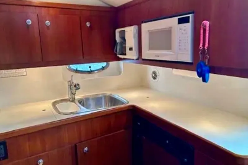  Yacht Photos Pics 2000 Tiara 37 Open yacht kitchen with sink, microwave, and wooden cabinets.