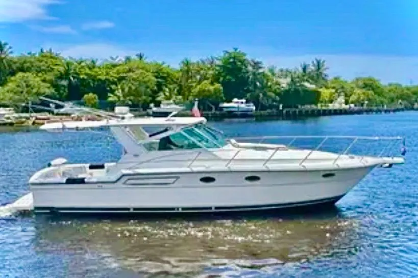 2000 Tiara 37 Open yacht cruising on a sunny day, surrounded by lush greenery.